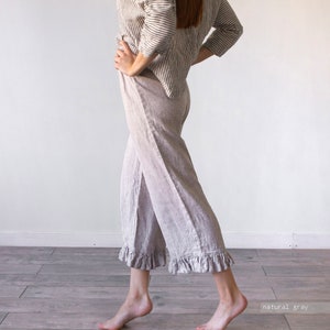 May include: Wide-leg linen pants with a ruffle trim at the hem. The pants are a light gray color and are made of a soft, comfortable fabric.