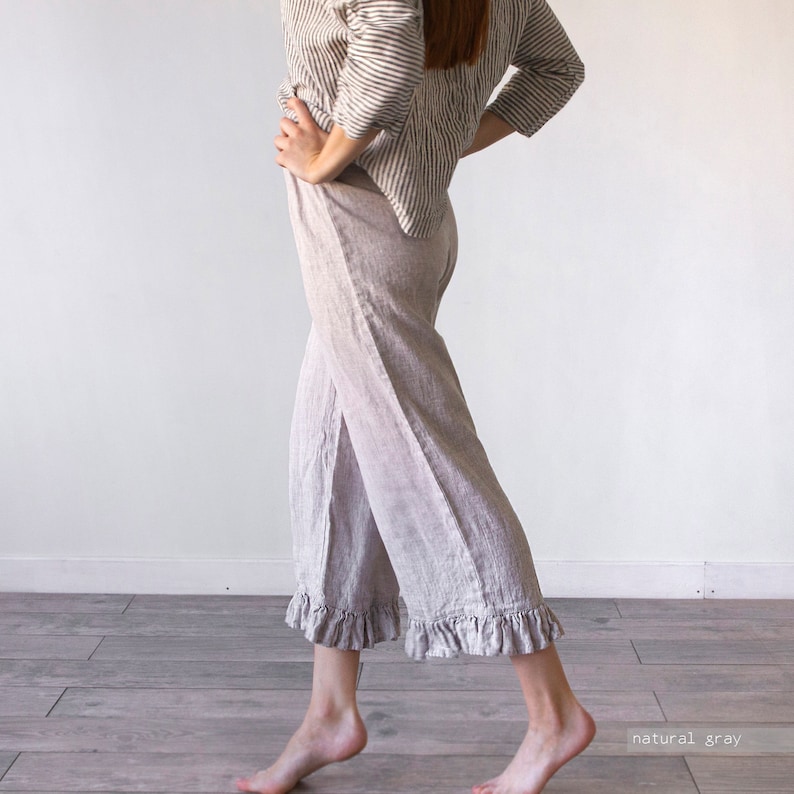 May include: Wide-leg linen pants with a ruffle trim at the hem. The pants are a light gray color and are made of a soft, comfortable fabric.