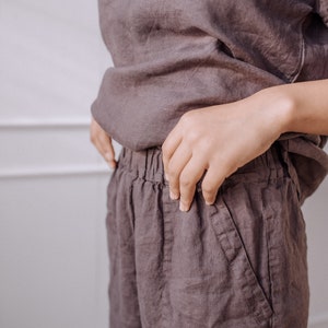 May include: A pair of loose-fitting, dark brown linen trousers with a drawstring waist and pockets.