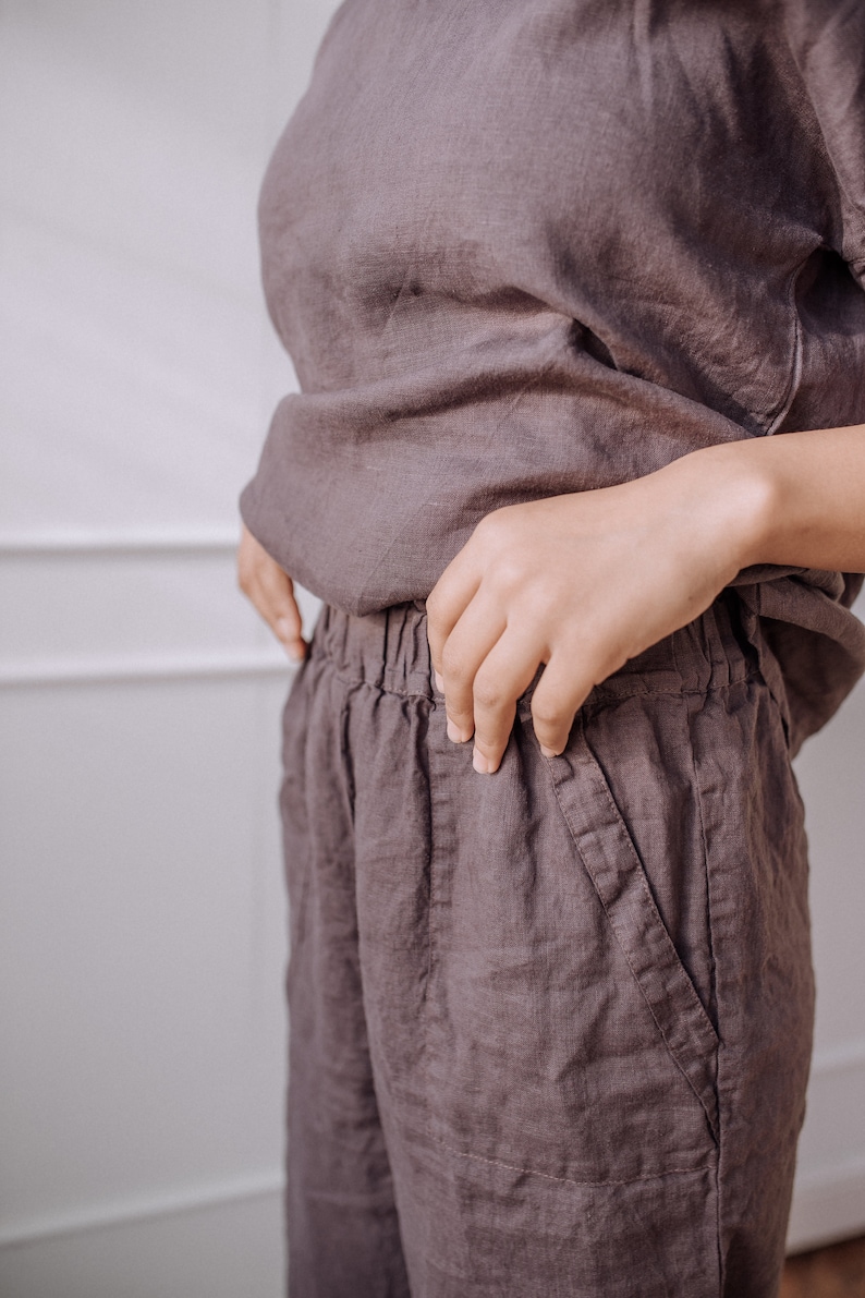 May include: A pair of loose-fitting, dark brown linen trousers with a drawstring waist and pockets.