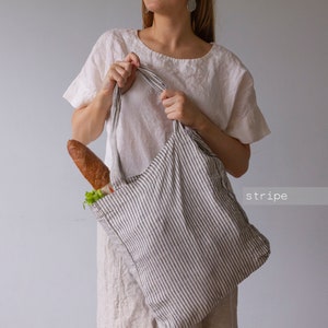 May include: A striped tote bag with a baguette and vegetables inside. The bag is gray and white with vertical stripes. The word "stripe" is in the lower right corner.