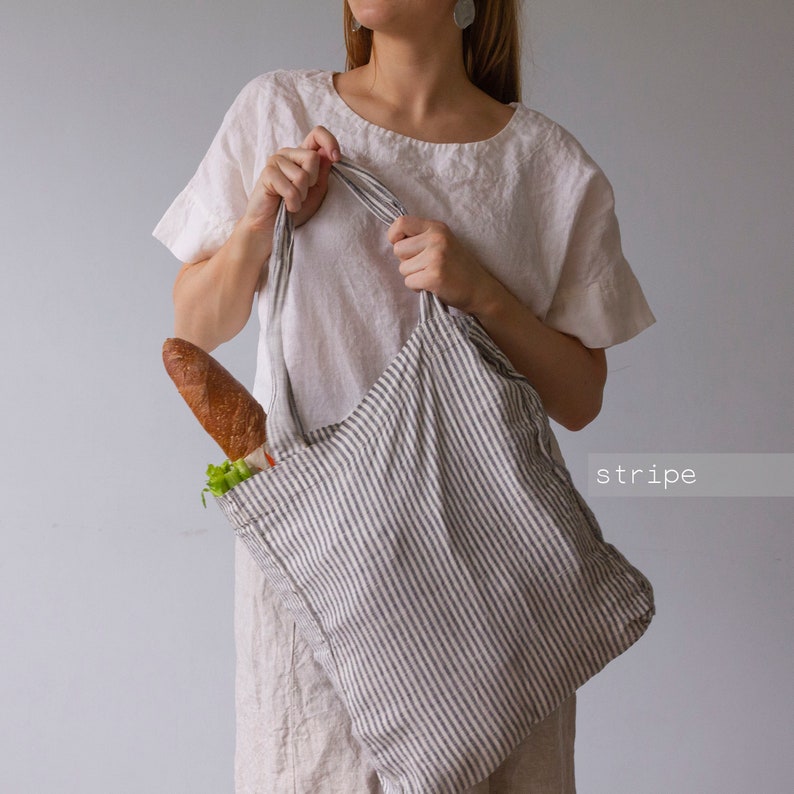 May include: A striped tote bag with a baguette and vegetables inside. The bag is gray and white with vertical stripes. The word "stripe" is in the lower right corner.