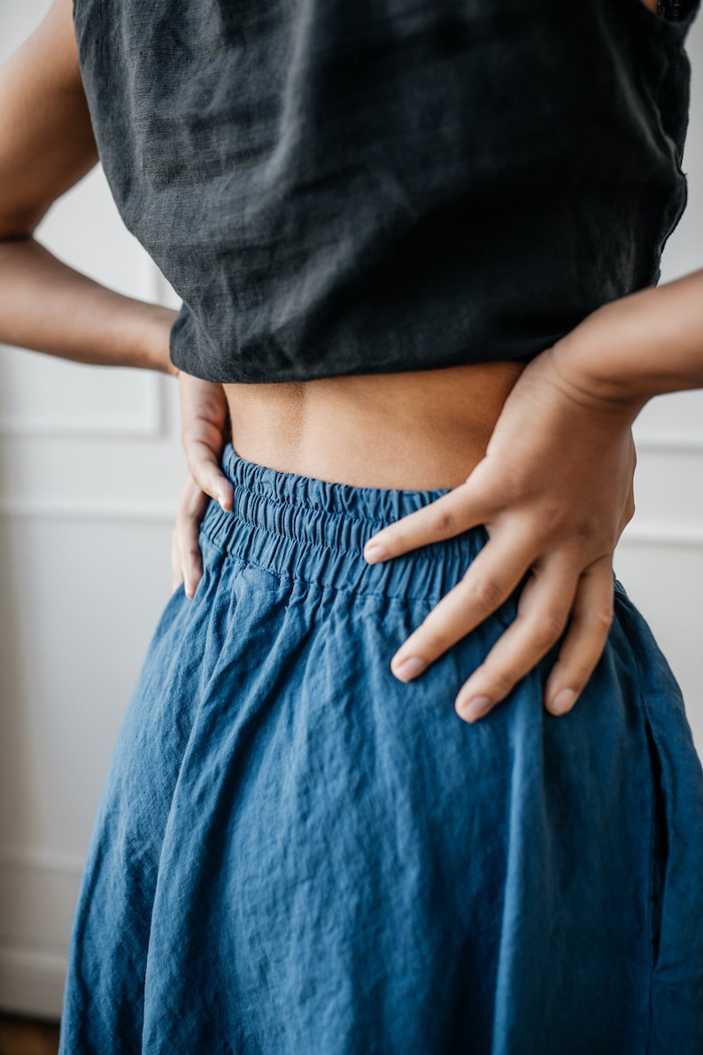 Pu&ograve; includere: Un top corto nero e una gonna blu. Il top &egrave; di colore nero pieno, e la gonna &egrave; di un blu vibrante con una fascia in vita arricciata. Il tessuto sembra leggero e fluido, suggerendo uno stile casual.