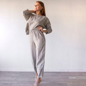 Pode incluir: Um conjunto de cal&ccedil;as e blazer de linho listrado com um caimento solto. As cal&ccedil;as t&ecirc;m cintura com cord&atilde;o e a parte de cima tem um decote de barco.