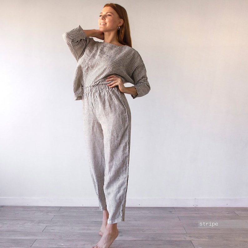 Pode incluir: Um conjunto de cal&ccedil;as e blazer de linho listrado com um caimento solto. As cal&ccedil;as t&ecirc;m cintura com cord&atilde;o e a parte de cima tem um decote de barco.