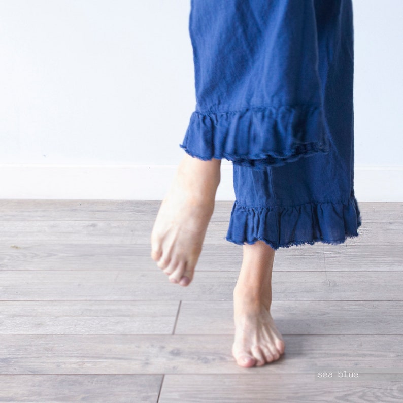 May include: A pair of blue linen pants with a ruffled hem. The pants are shown on a person standing on a wood floor. The text "sea blue" is visible in the lower right corner of the image.