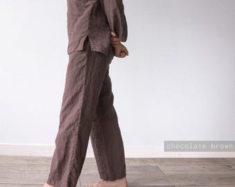 Puede incluir: Un conjunto de camisa de manga larga y pantalón a juego en color marrón chocolate, confeccionado en tejido texturizado. La camisa presenta una abertura lateral en el dobladillo y el pantalón tiene un corte recto. Texto "chocolate brown" visible.
