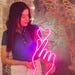 May include: A pink neon sign shaped like a hand making a pinky promise gesture with a heart on the index finger.
