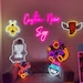 May include: A collection of neon signs with various designs, including a bee, a tombstone with the text "Never Trust the Living", a pizza with wings, a cartoon astronaut, and the text "Custom Neon Sign".