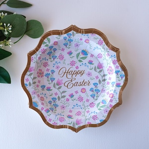 May include: A white paper plate with a gold rim and a floral pattern. The plate has the text "Happy Easter" in gold lettering.
