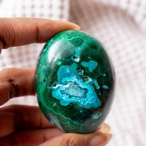 May include: A smooth, green and blue malachite egg-shaped crystal. The crystal has a swirling pattern of green and blue.