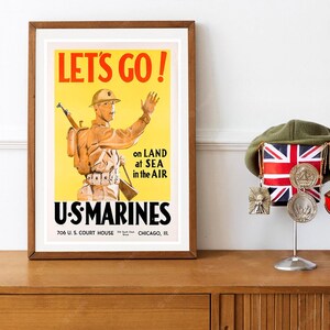May include: A framed vintage U.S. Marines recruitment poster with the text "LET'S GO!" and an illustration of a soldier. A green beret with a Union Jack and medals is displayed on a stand.