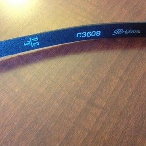 Op de afbeelding: Zwarte leren riem met de tekst "1 3/4" en "C3608 Brighton" in wit gedrukt.