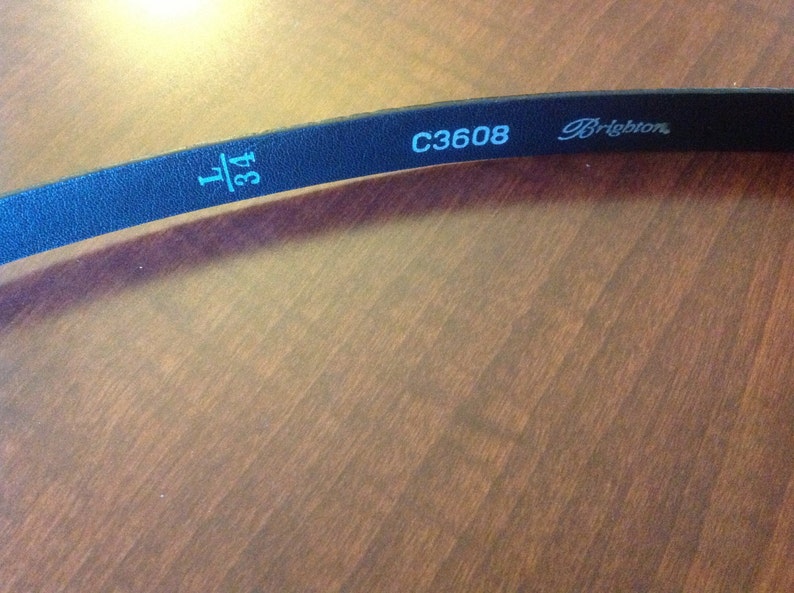 Op de afbeelding: Zwarte leren riem met de tekst "1 3/4" en "C3608 Brighton" in wit gedrukt.