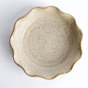 May include: A white ceramic pie dish with a scalloped edge and a speckled glaze.