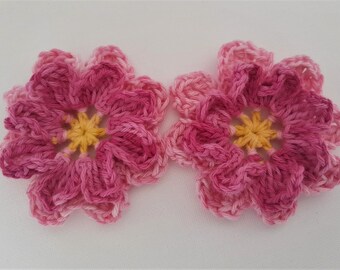 May include: Two crocheted pink and yellow flowers with a ruffled edge.