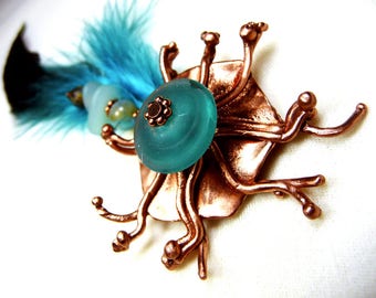 Broche en cuivre et plume bleue et vert-bronze