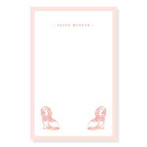 Könnte beinhalten: Rosa-farbenes Briefpapier mit rosa Rand und dem Namen "PAIGE MINEAR" in der Mitte. Zwei rosa florale Hundeillustrationen befinden sich am unteren Rand der Seite.