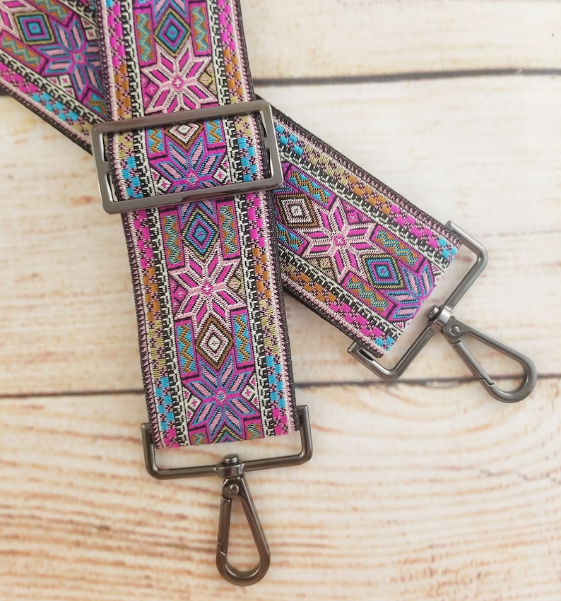 May include: Two colorful patterned fabric straps with silver metal clasps. The straps have a geometric design with pink, blue, and gold accents.