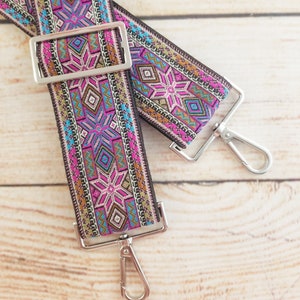 May include: A pair of colorful patterned adjustable straps with silver metal clasps. The straps are made of woven fabric with a geometric design in shades of pink, blue, brown, and gold.