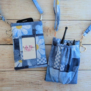 May include: Two denim crossbody bags with daisy and checkered patterns. One bag holds a phone, the other contains black accessories. Both have adjustable straps and heart-shaped charms. The bags feature the text "Katie Rene Designs".