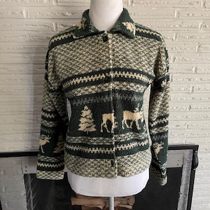 May include: A green and white patterned sweater with a button-up front. The sweater features a design of trees and deer.