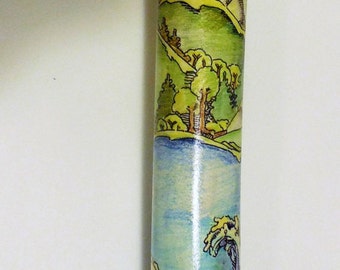 May include: A wooden walking stick with a decorative design. The stick is painted with a blue sky, green hills, and a yellow mountain. The bottom of the stick is black.