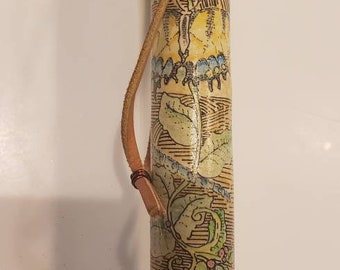 May include: A walking stick with a brown leather strap and a decorative design featuring a dragonfly, leaves, and flowers in shades of green, yellow, and blue.