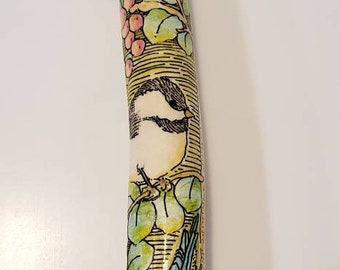 Puede incluir: Un bastón de senderismo con una base blanca y un diseño pintado a mano de pájaros y hojas. El diseño presenta un pájaro azul, un pájaro blanco y hojas verdes sobre un fondo amarillo.