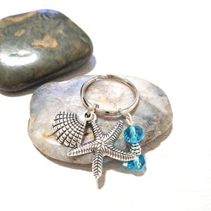 Sleutelhanger met strandthema, hanger in de vorm van een zeester en een schelpje, aquablauwe kristallen glaskralen, tas- en autoaccessoires met strand- en kustthema.