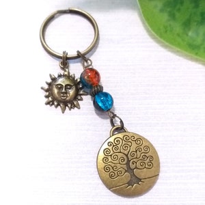 May include: A bronze key chain with a sun charm, blue and orange glass beads, and a tree of life charm.