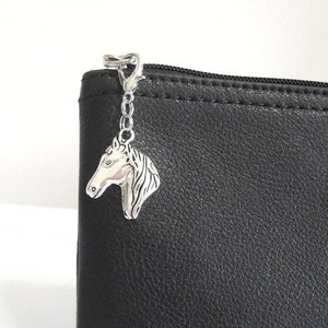 May include: Black leather zippered pouch with a silver horse charm attached to the zipper pull.