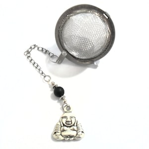 May include: Silver tea infuser with a chain and a small silver Buddha charm. The infuser has a black bead on the chain.