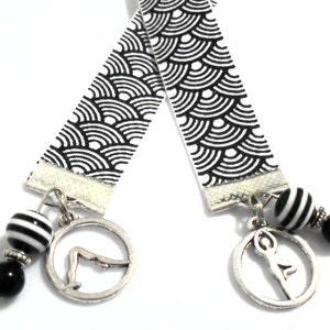 Black and white grostain ribbon bookmark with 2 different silver tone metal yoga or pilates poses.  Black and white resin beads and glass beads were used.  Th length of the ribbon is 11 inches and the total length is 13-14 inches.