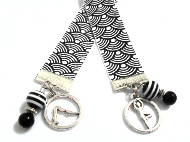 Black and white grostain ribbon bookmark with 2 different silver tone metal yoga or pilates poses.  Black and white resin beads and glass beads were used.  Th length of the ribbon is 11 inches and the total length is 13-14 inches.