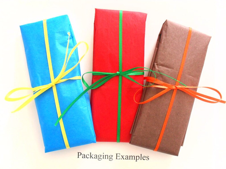 May include: Three gift boxes wrapped in different colors of tissue paper with matching ribbon. The boxes are blue, red, and brown. The blue box has yellow ribbon, the red box has green ribbon, and the brown box has orange ribbon. The text "Packaging Examples" is printed below the boxes.