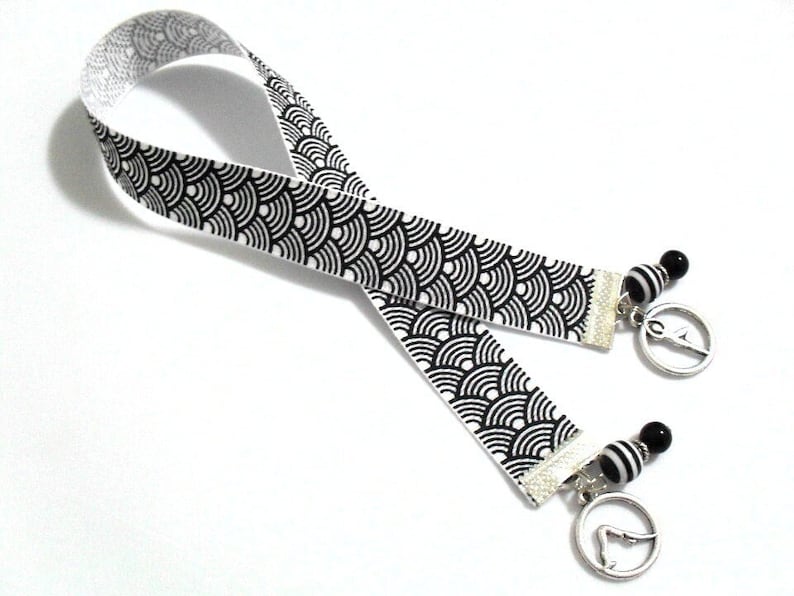 This yoga and pilates ribbon bookmark with metal charms in various yoga poses would be enjoyed by the spiritual person.  A unique item for yoga and pilates instructors.  

The black and white grosgrain ribbon is 11 inches (28cm) in length.   The total length of the bookmark is 13-14 inches (33-36cm).  The width of the ribbon is 5/8 inches (16mm).  The solid black beads are glass and the black/white striped beads are of a resin material.