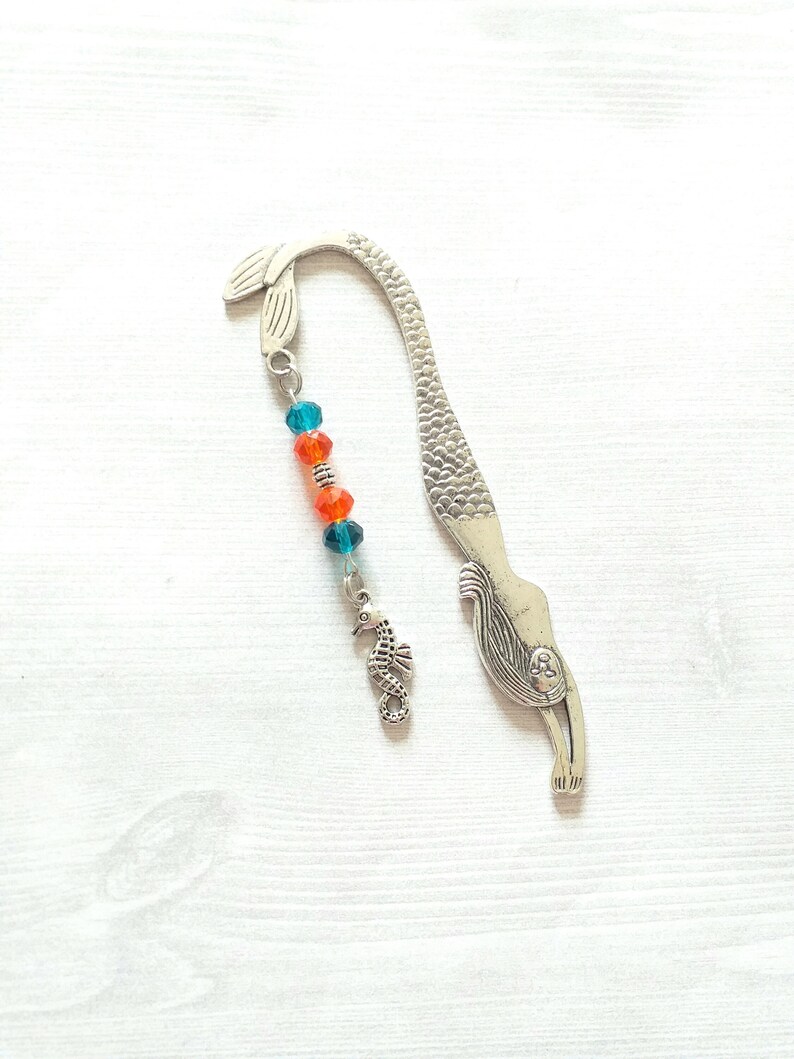 Mermaid metal bookmark book hook with silver tone seahorse charm.  Durable mythical mermaid tail book mark with teal blue and orange crystal beads.  A great beaded accessory for swimmers and beach lovers.  Measures 5 inches.