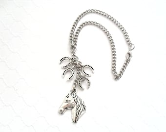 May include: A silver-toned metal chain necklace featuring a horse head pendant and three smaller horseshoe charms. The necklace has a standard link chain design with a lobster claw clasp, all rendered in a polished silver-colored metallic finish.