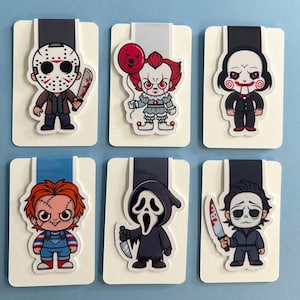 May include: A set of six magnetic bookmarks featuring cartoon-style horror movie characters including Jason Voorhees with a bloody machete, Pennywise with a red balloon, Billy the Puppet, Chucky, Ghostface with a knife, and Michael Myers.