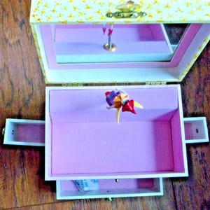 Adorable "Just In Case" Fairy Musical Treasure Box with four secret drawers in which girls can storage their tiny treasures.
The little fairy figurine moves with the melody that rings out.  
Measures: 6" x 6" x 4" W.  New in the original box.
 Was opened only to take the photos.