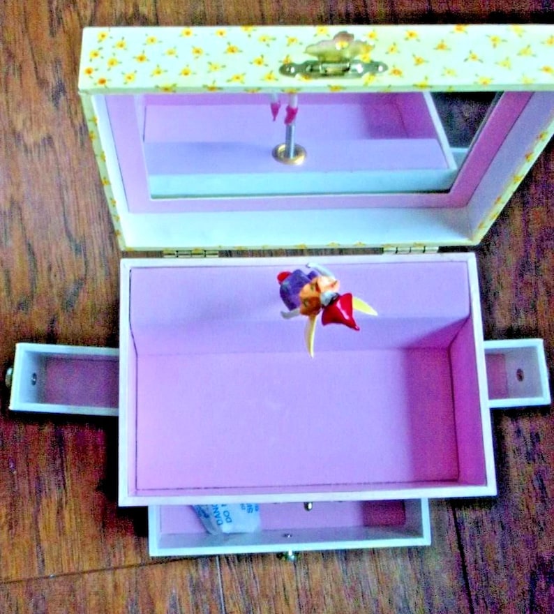 Adorable "Just In Case" Fairy Musical Treasure Box with four secret drawers in which girls can storage their tiny treasures.
The little fairy figurine moves with the melody that rings out.  
Measures: 6" x 6" x 4" W.  New in the original box.
 Was opened only to take the photos.