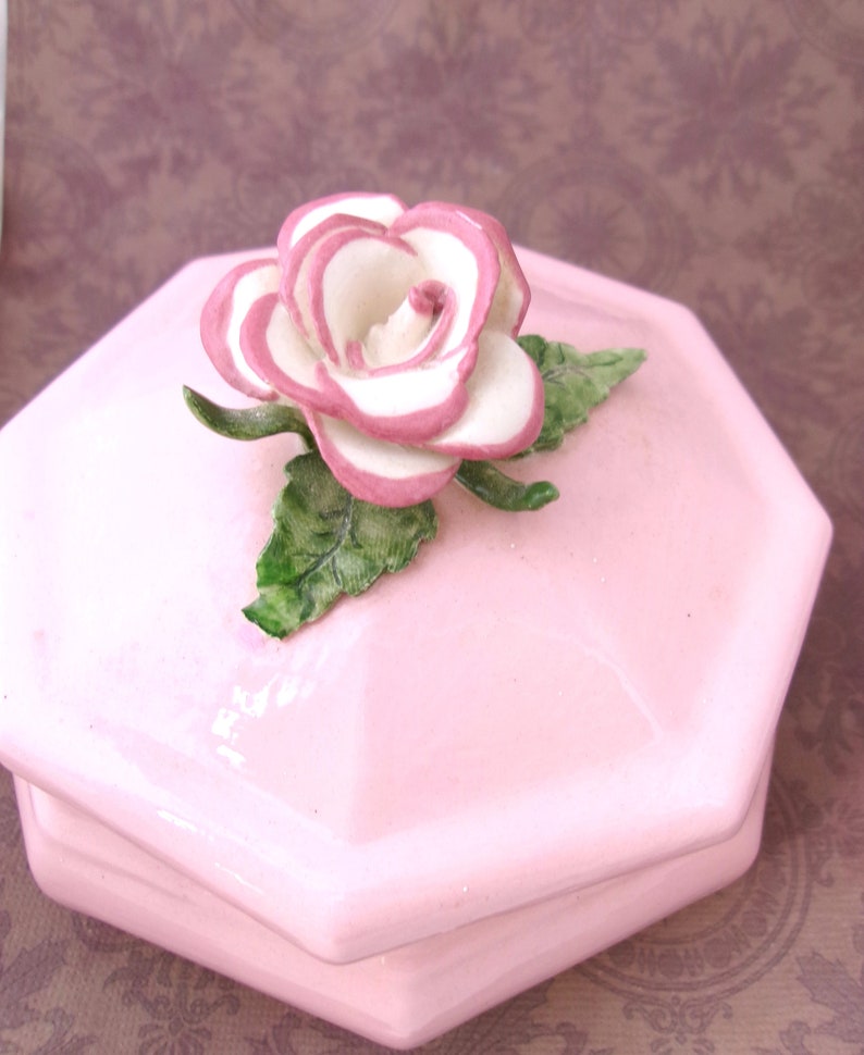 Gorgeous, Vintage in excellent condition. Just a minor chip on one of the leaves, the tip was broken and painting using the same color. Please see the last photo. (bright pink photo)
Measures 5"diameter and 4.25"H including the rose on lid.