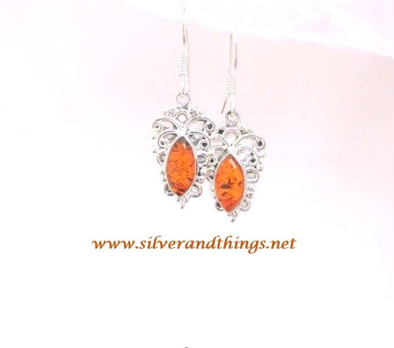 Handmade of natural Baltic Amber and sterling silver.  Fine silver work with amazing details around the gems.
Measures approx. 1in L x  1/2in W.
 they drop 1.52 inches