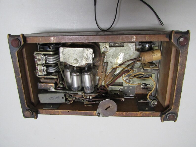 Puede incluir: Se ven los componentes internos de una radio antigua, que muestran v&aacute;lvulas de vac&iacute;o, cableado y un condensador de sintonizaci&oacute;n dentro de un marco de madera. El interior de la radio es una compleja disposici&oacute;n de piezas electr&oacute;nicas.