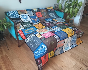 Può includere: Una trapunta ricordo realizzata con vari pannelli di magliette colorate con diverse stampe grafiche e testi, tra cui Exeter Water Polo, Muhlenberg Swimming and Diving ed Exeter Marching Band 2019. La trapunta ha un bordo e un retro neri.