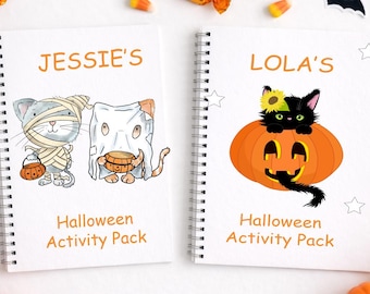 Op de afbeelding: Twee witte spiraalgebonden notitieboeken met de titel Halloween Activity Pack. Het linkerboek zegt JESSIE'S en toont een mummiekat en een spookkat. Het rechterboek zegt LOLA'S en toont een zwarte kat die in een pompoen met gezicht zit.