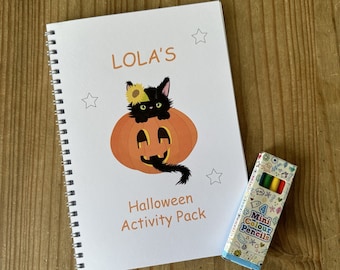May include: A white spiral bound book with the text "LOLA'S Halloween Activity Pack" and a black cat with a sunflower on its head sitting inside a jack-o-lantern. A small box of 4 mini colored pencils is next to the book.