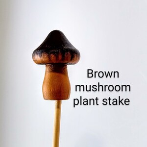 K&ouml;nnte beinhalten: Brauner, pilzf&ouml;rmiger Pflanzenstab. Der Pilz ist braun mit schwarzen Streifen bemalt. Der Stab ist aus Holz.