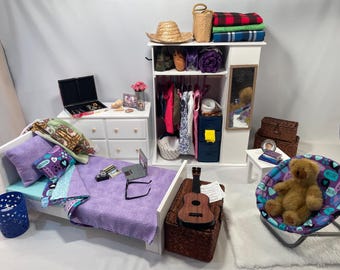 May include: A dollhouse bedroom set with a white bed, dresser, and closet. The bed has a purple and blue bedding set with a pillow that says "Sweet Dreams". The closet has a mirror and shelves with clothes and accessories. There is a teddy bear sitting in a purple and blue chair.